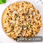 top down view of mushroom stroganoff piled high on round white plate garnished with parsley.