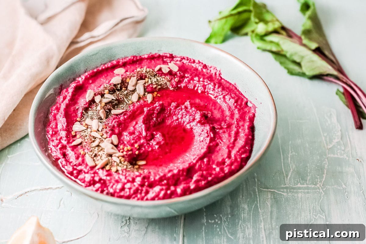 Beet Hummus: Vibrant, Versatile, Delicious 5 A large, inviting bowl of easy beet hummus, elegantly garnished with a delicate swirl of olive oil and a sprinkle of seeds, ready to be enjoyed.