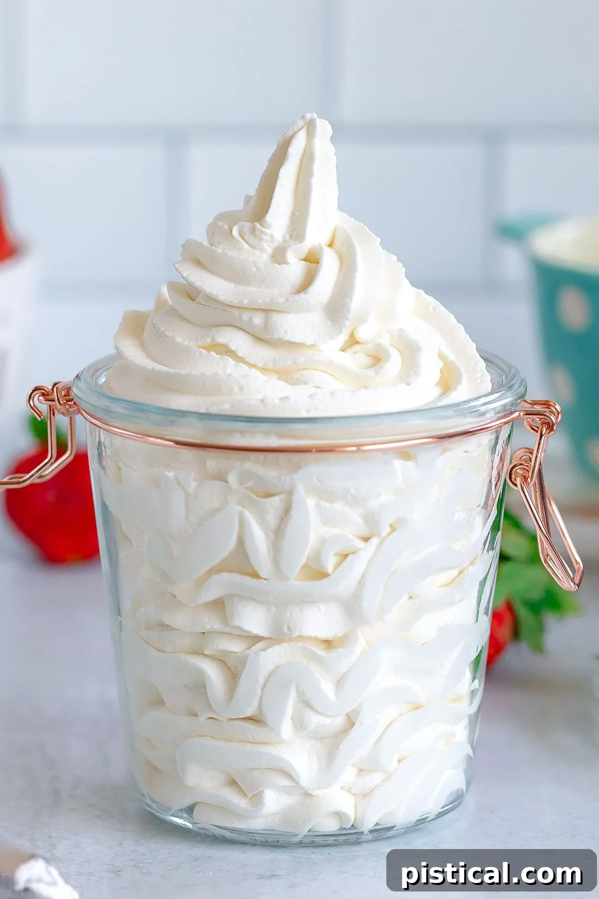 Stiff whipped cream piped into a tall glass jar with a gold hinge lid.