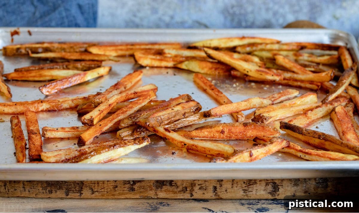 golden and crispy oven baked french fries on large baking sheet.