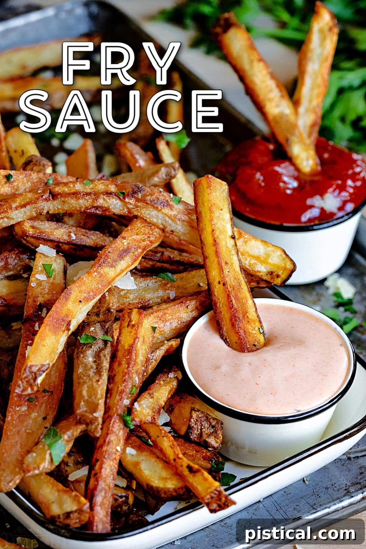 Crispy French fries on a baking sheet, with small bowls of homemade fry sauce and classic ketchup, ready for dipping.