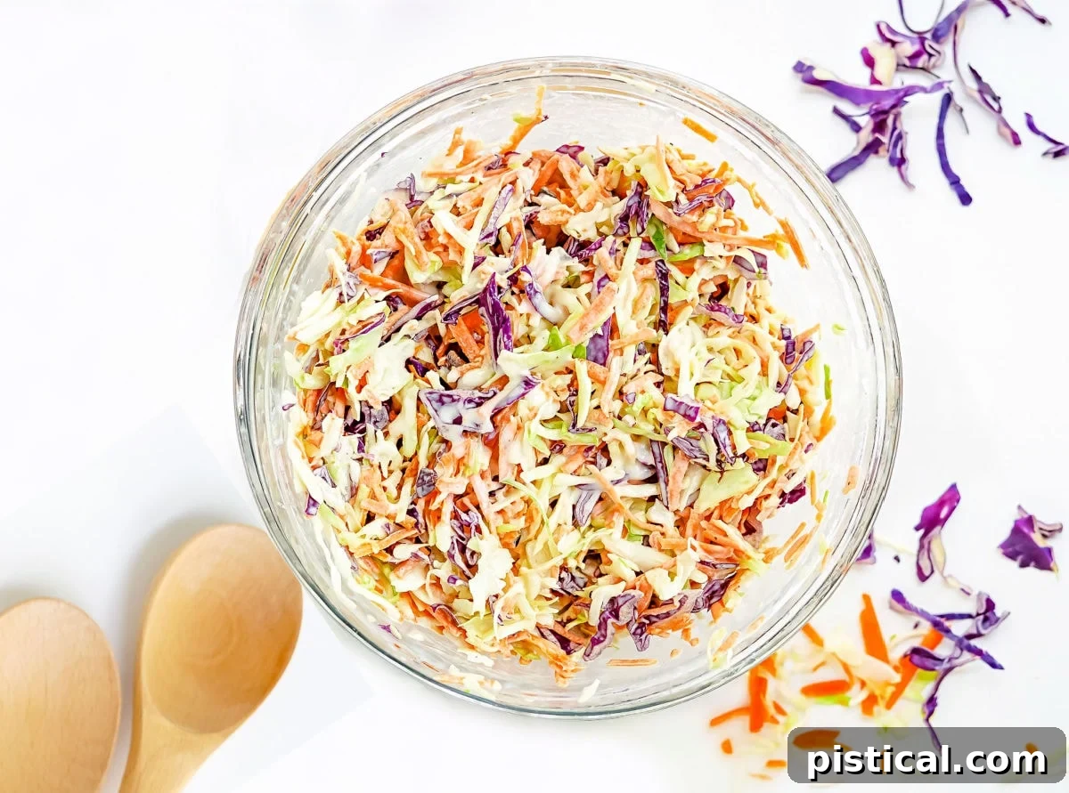 Creamy coleslaw tossed together and presented in a large glass mixing bowl, showcasing its fresh ingredients.
