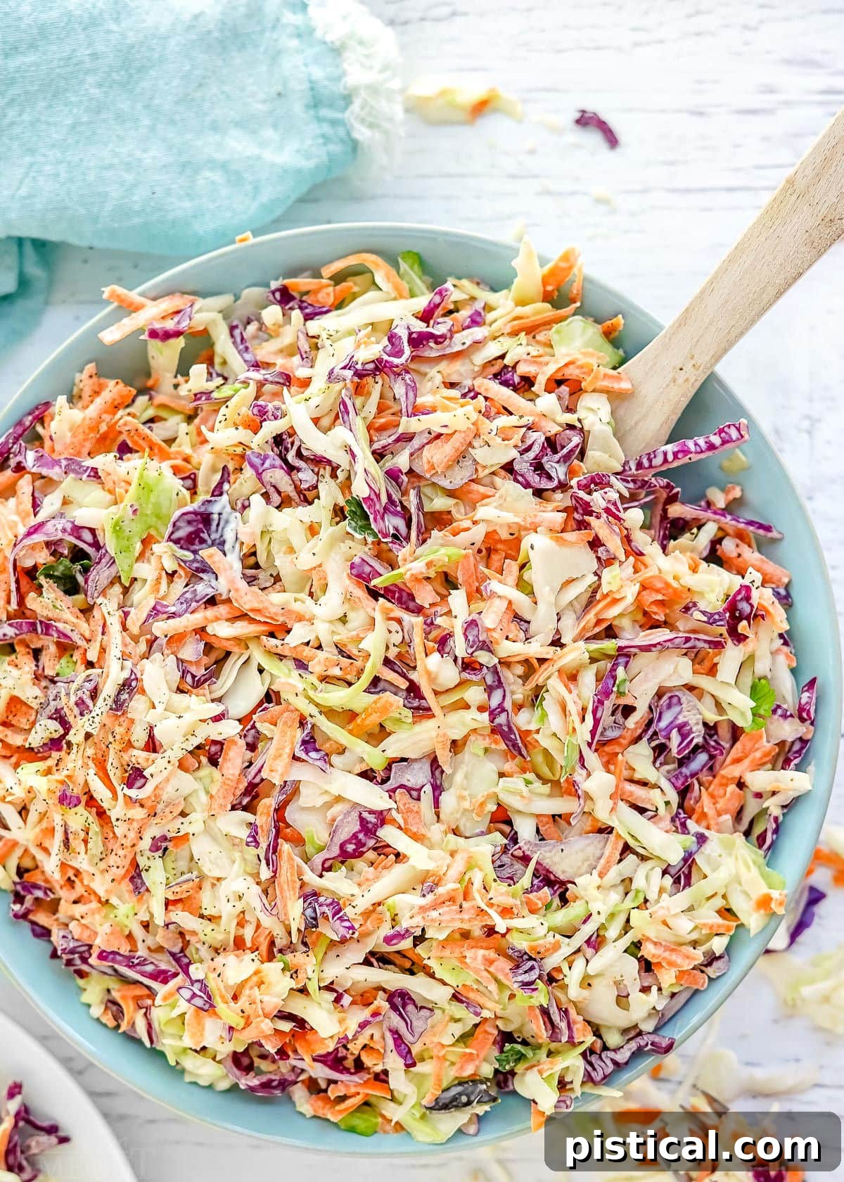 A close-up view of vibrant, tri-colored coleslaw in a light blue bowl, perfectly mixed and ready to be served.