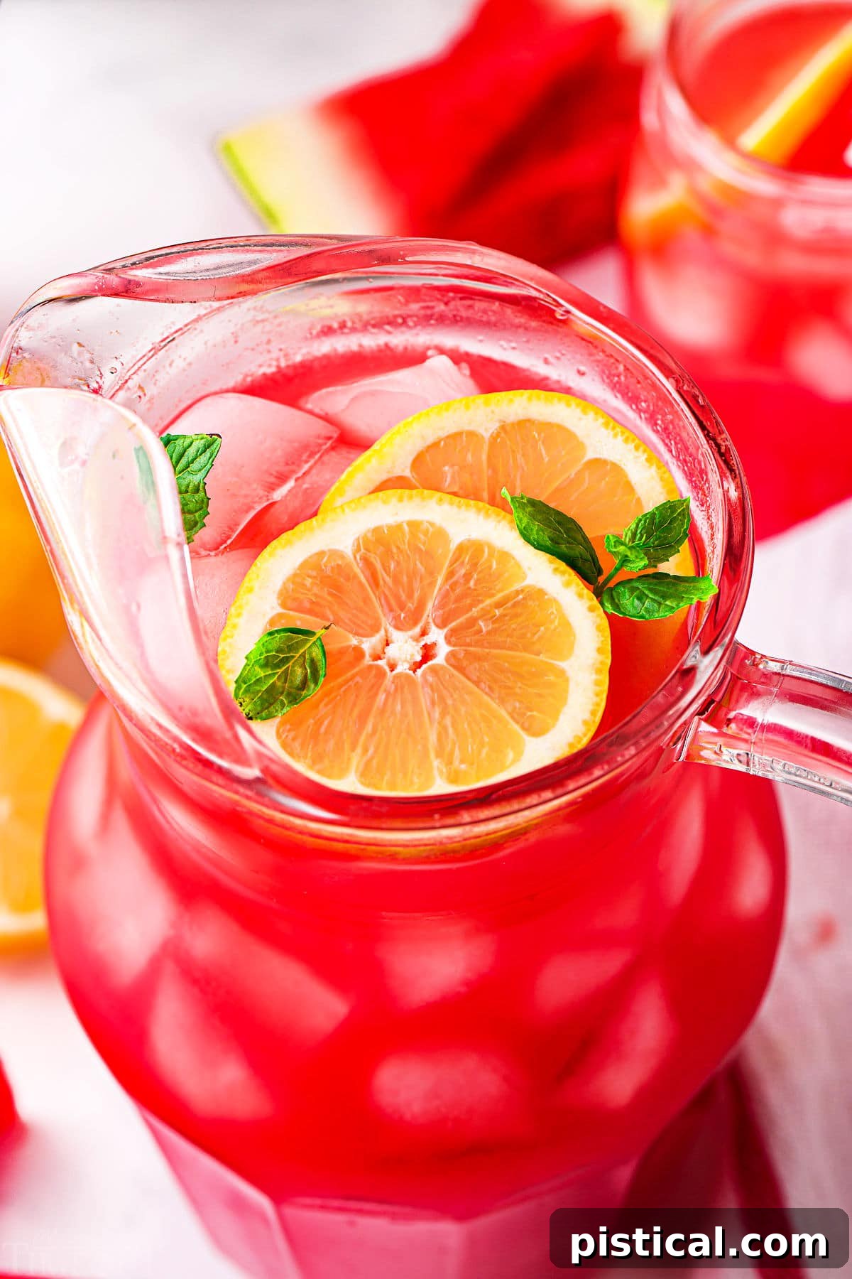 A top-down view of a glass pitcher filled with vibrant watermelon lemonade, garnished with fresh fruit, showcasing its appealing color and inviting texture.