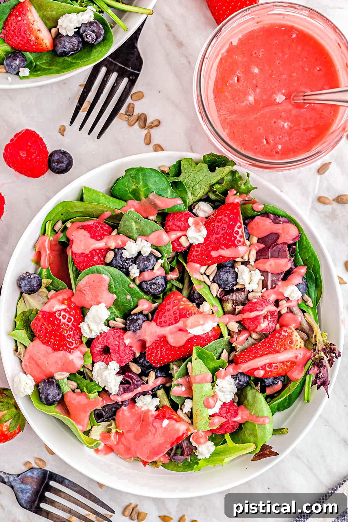A top-down view of a vibrant berry salad, generously drizzled with raspberry vinaigrette, ready to be served and enjoyed.