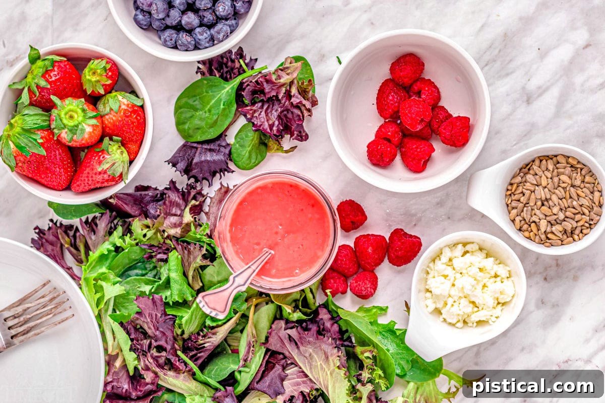 Various fresh berry salad ingredients, including spinach, mixed greens, blueberries, raspberries, strawberries, goat cheese, and sunflower seeds, artfully arranged in separate bowls on a elegant marble surface.