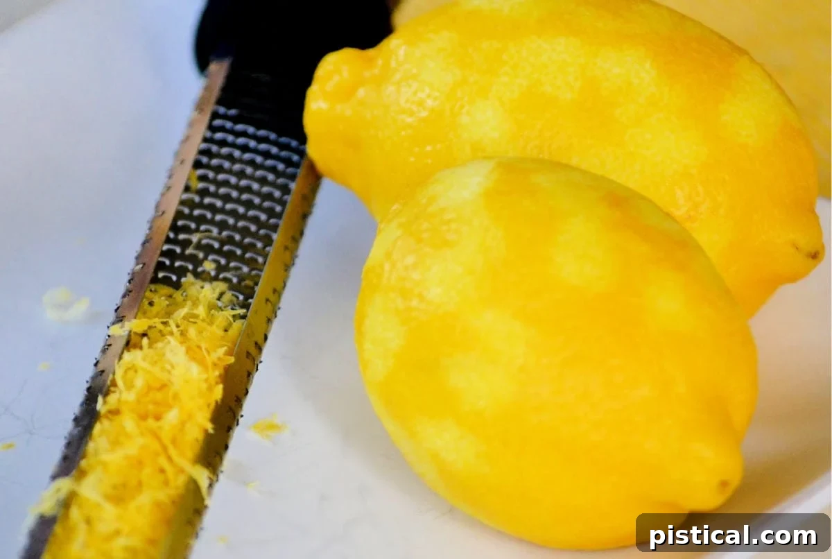 Zesty Lemon Pasta 4 lemon being zested on white plate with microplane