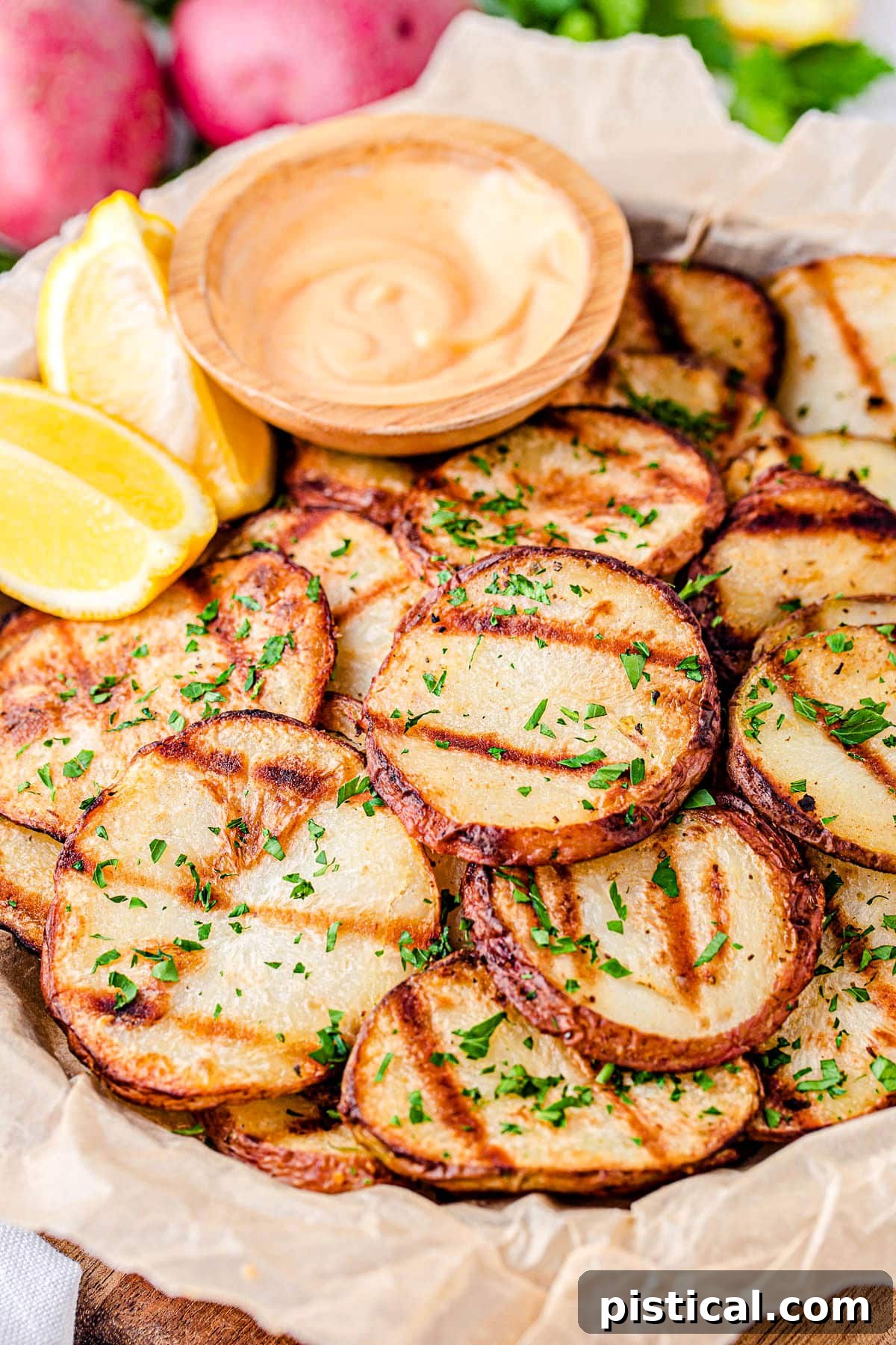 grilled potatoes served with spicy mayo dip and lemon wedges on wood tray.