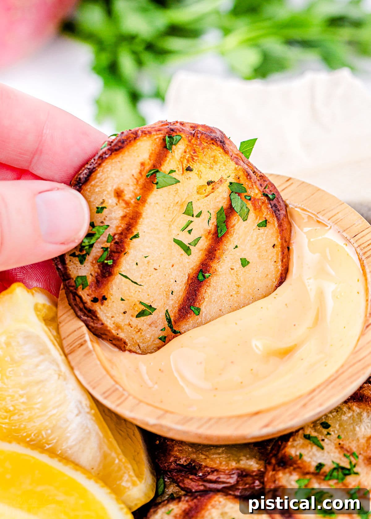 grilled potato slice being dipped in spicy mayo dip.