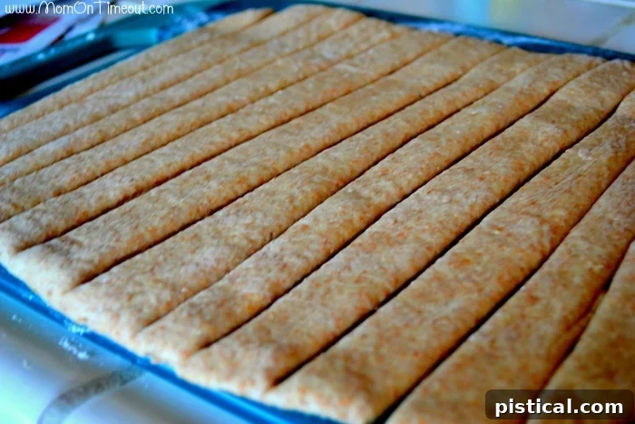 Dough cut into uniform strips, ready to be wrapped around sausages for baking