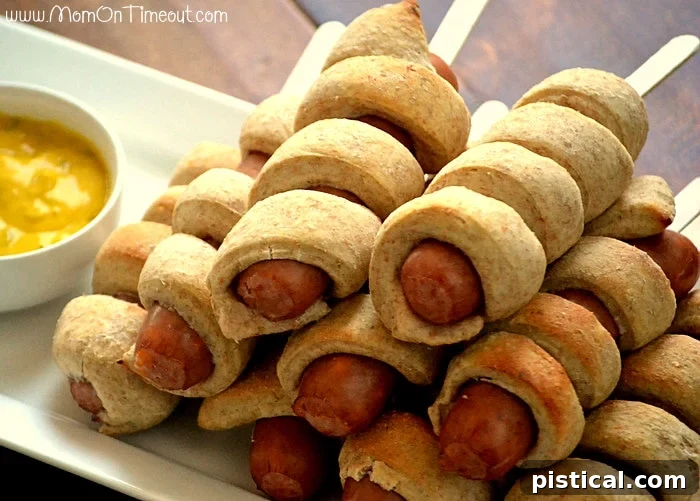 Close-up of baked Spiral-Wrapped Sausage on a Stick with dipping sauce, ready to serve at a party