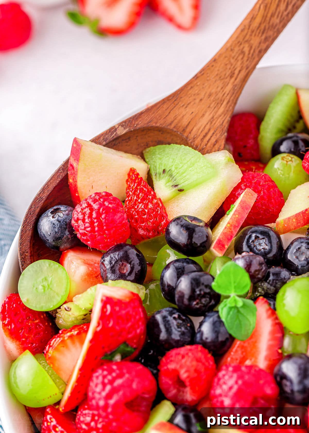 Nature's Candy Bowl 3 A spoonful of fresh fruit salad, showcasing a delightful mix of vibrant colors and textures, ready to be enjoyed from a serving bowl.