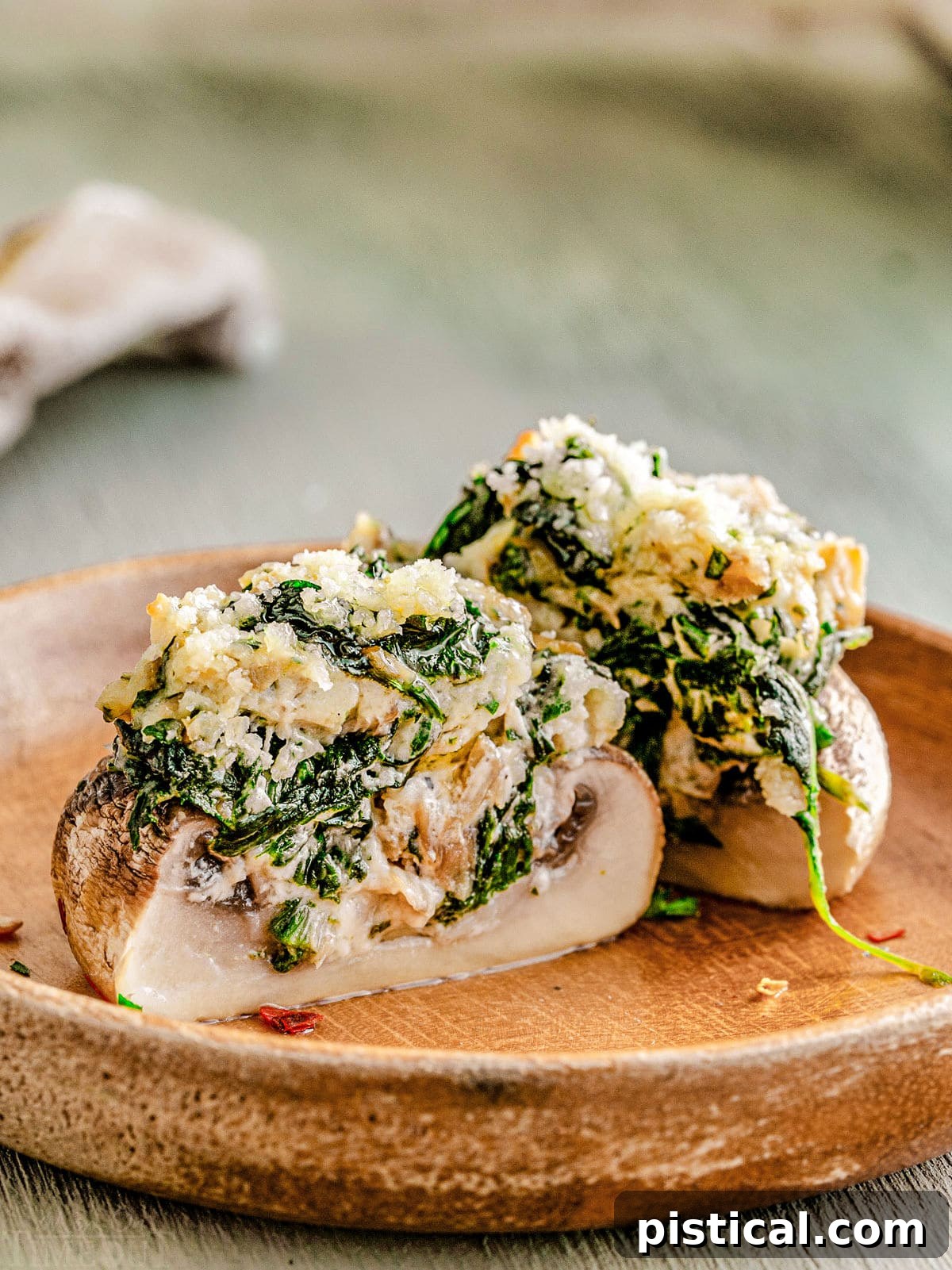 Silky Stuffed Mushrooms with Herbs and Garlic 6 a stuffed mushroom split in half on a brown plate so you can see the creamy spinach filling.
