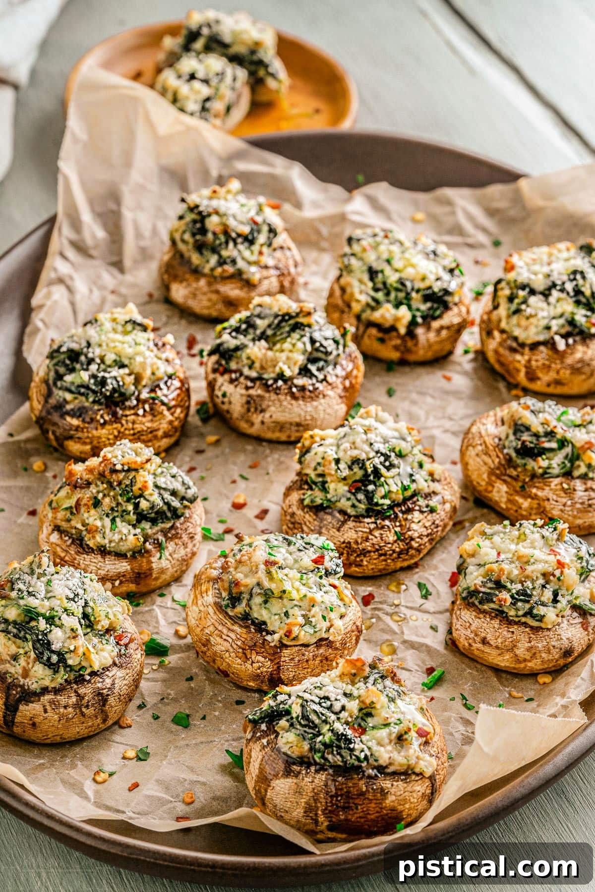 Silky Stuffed Mushrooms with Herbs and Garlic 7 tray full of stuffed mushrooms sitting on crumpled brown parchment paper and sprinkled with fresh parsley.
