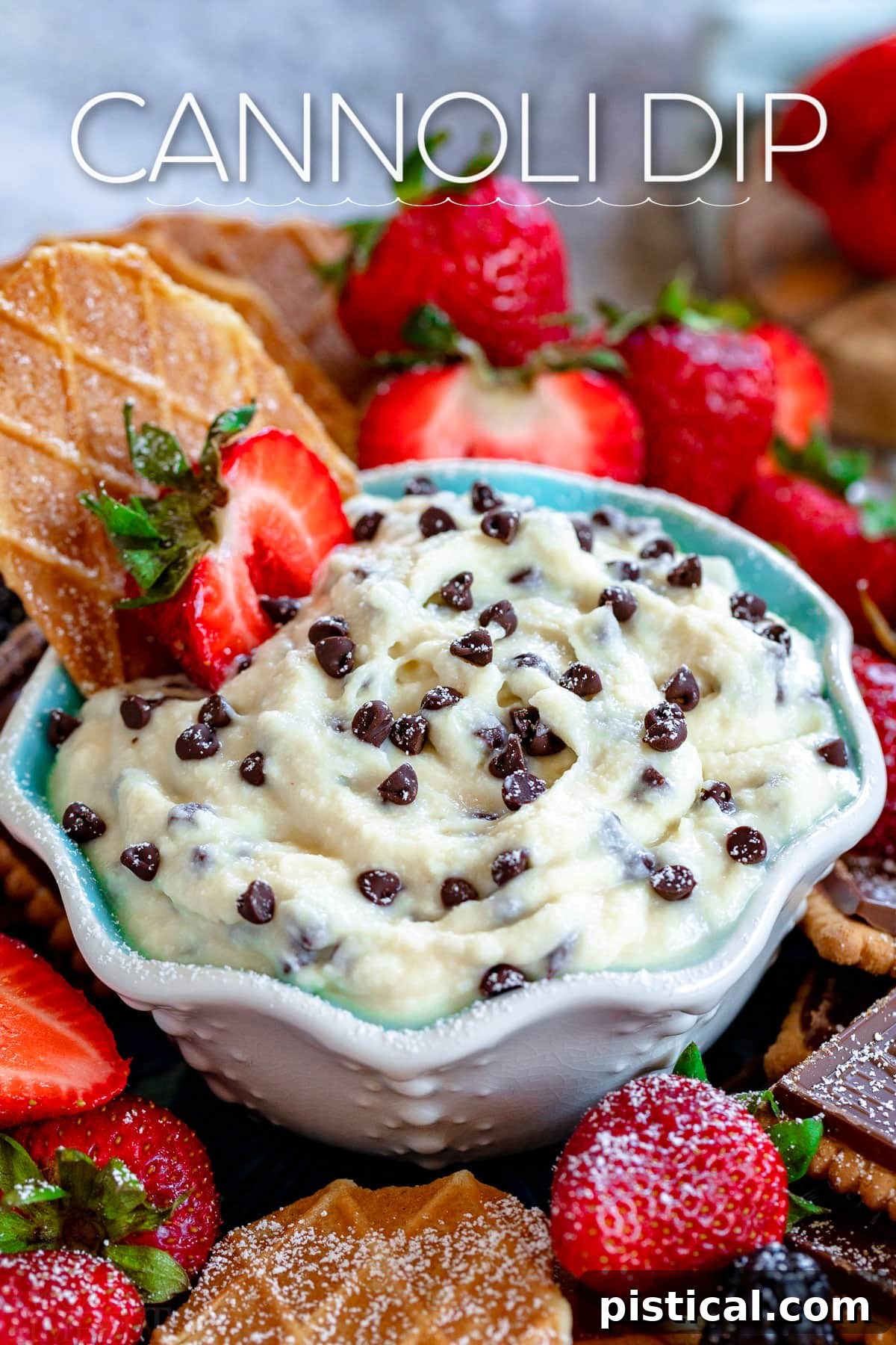 Decadent Cannoli Dip 2 Creamy Cannoli Dip served in a small white and blue bowl, elegantly surrounded by fresh, vibrant strawberries and crispy pizzelle cookies, inviting guests to dip and enjoy.