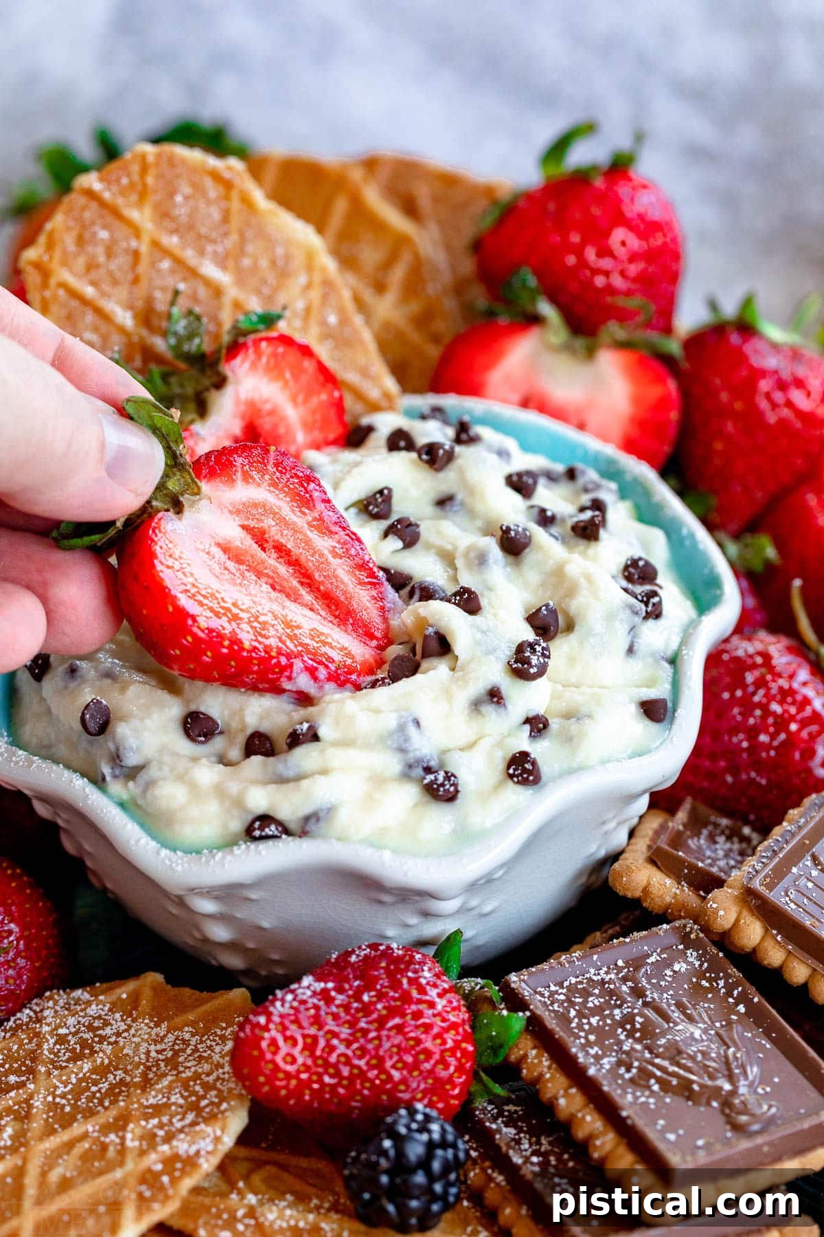 Decadent Cannoli Dip 6 A vibrant, fresh strawberry half being gracefully dipped into a pristine bowl of creamy Cannoli Dip, showcasing its delightful texture and inviting presentation, ready to be enjoyed.