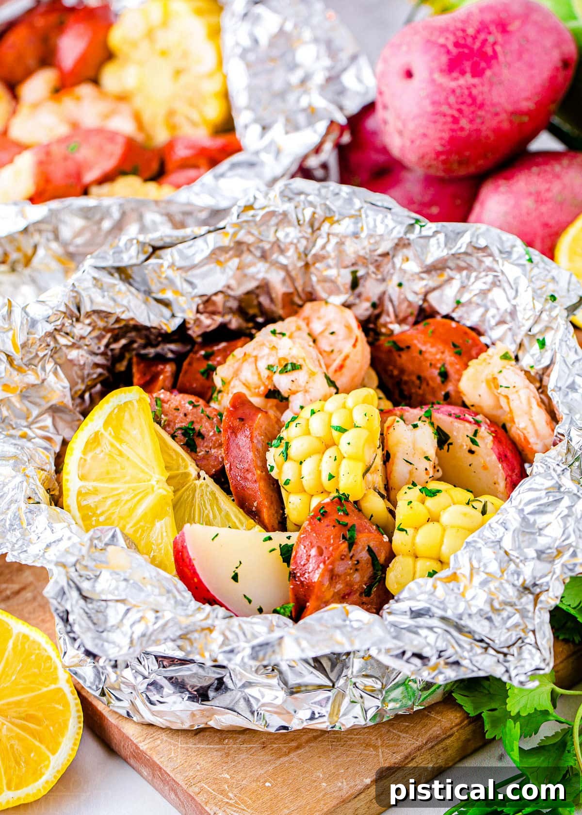 Grilled shrimp boil made in foil packets with corn, sausage, and shrimp, captured during the cooking process on a grill.