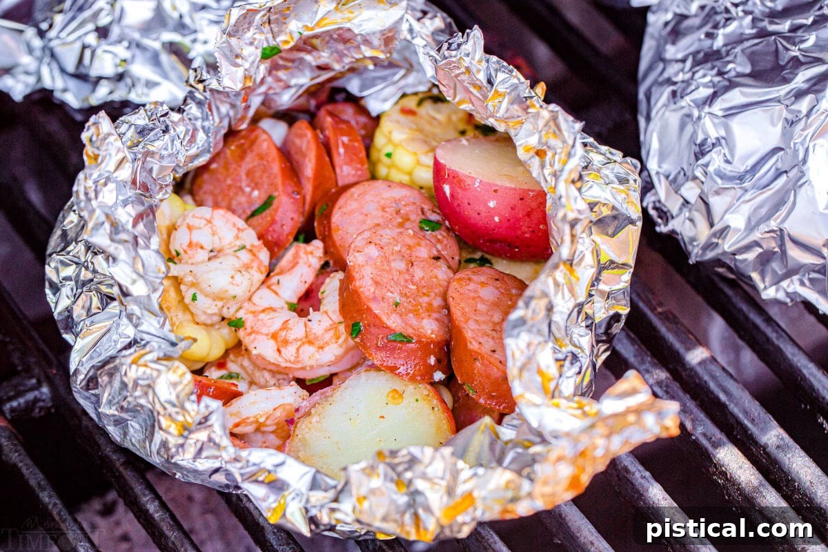 Shrimp foil packets being prepared on the grill, showing a hand placing a packet onto the hot grates.