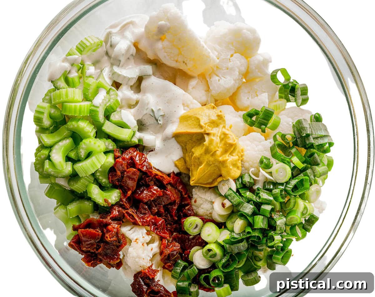 All prepared salad ingredients in a large glass bowl, ready to be mixed together.