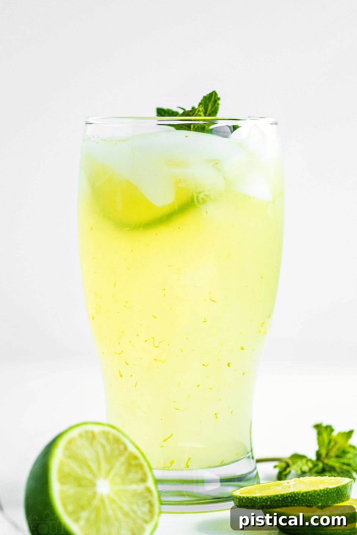 Quick and Refreshing Two Ingredient Limeade 6 tall glass of freshly made limeade garnished with a sprig of mint and fresh lime slices sitting in front of pitcher of limeade.