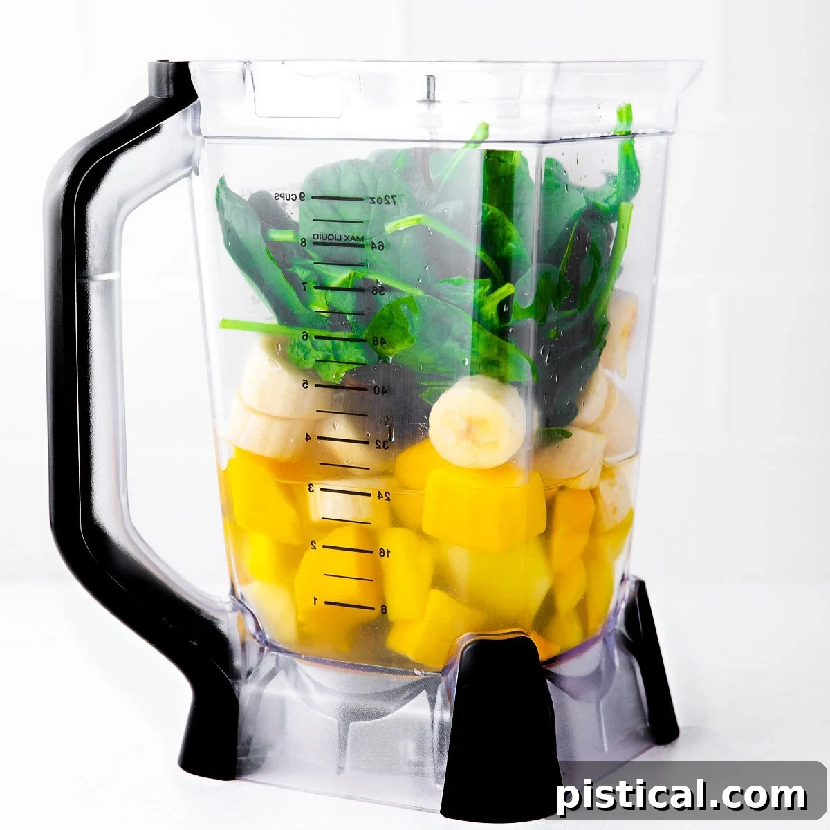 A blender filled with vibrant green smoothie ingredients, including leafy greens and tropical fruits, poised for blending.