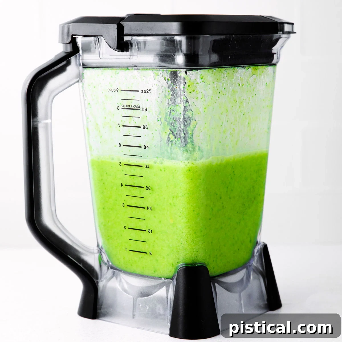 A vibrant green smoothie in a sleek blender with black accents, perfectly blended and ready to be served, highlighting its fresh, healthy appearance.