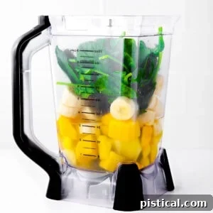 Blender with green smoothie ingredients inside, ready for blending.