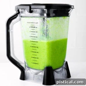 Green smoothie in the blender, now perfectly blended and ready to pour.