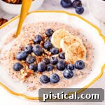 Close up look at steel cut oats in bowl topped with blueberries, banana slices and pecans.