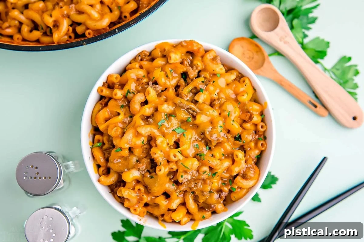 homemade hamburger helper served in a small white bowl on a mint green background.