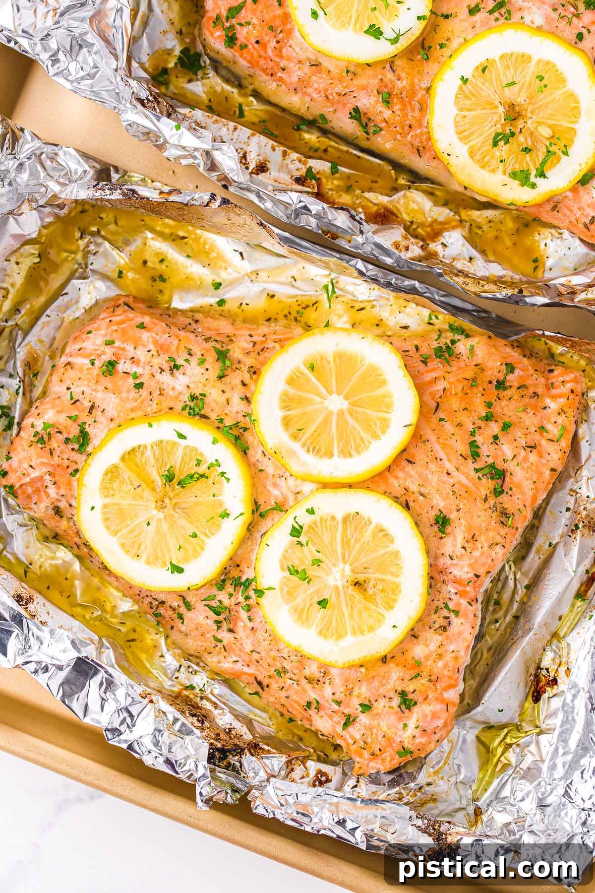 baked salmon in foil topped with lemon slices and fresh parsley. 