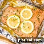 baked salmon in foil topped with lemon slices and fresh parsley.