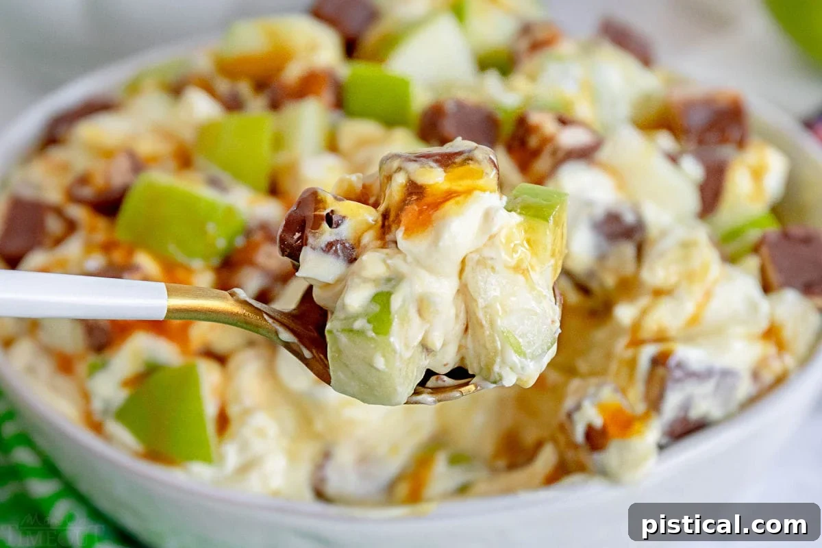 spoonful of caramel apple salad held in front of serving bowl.
