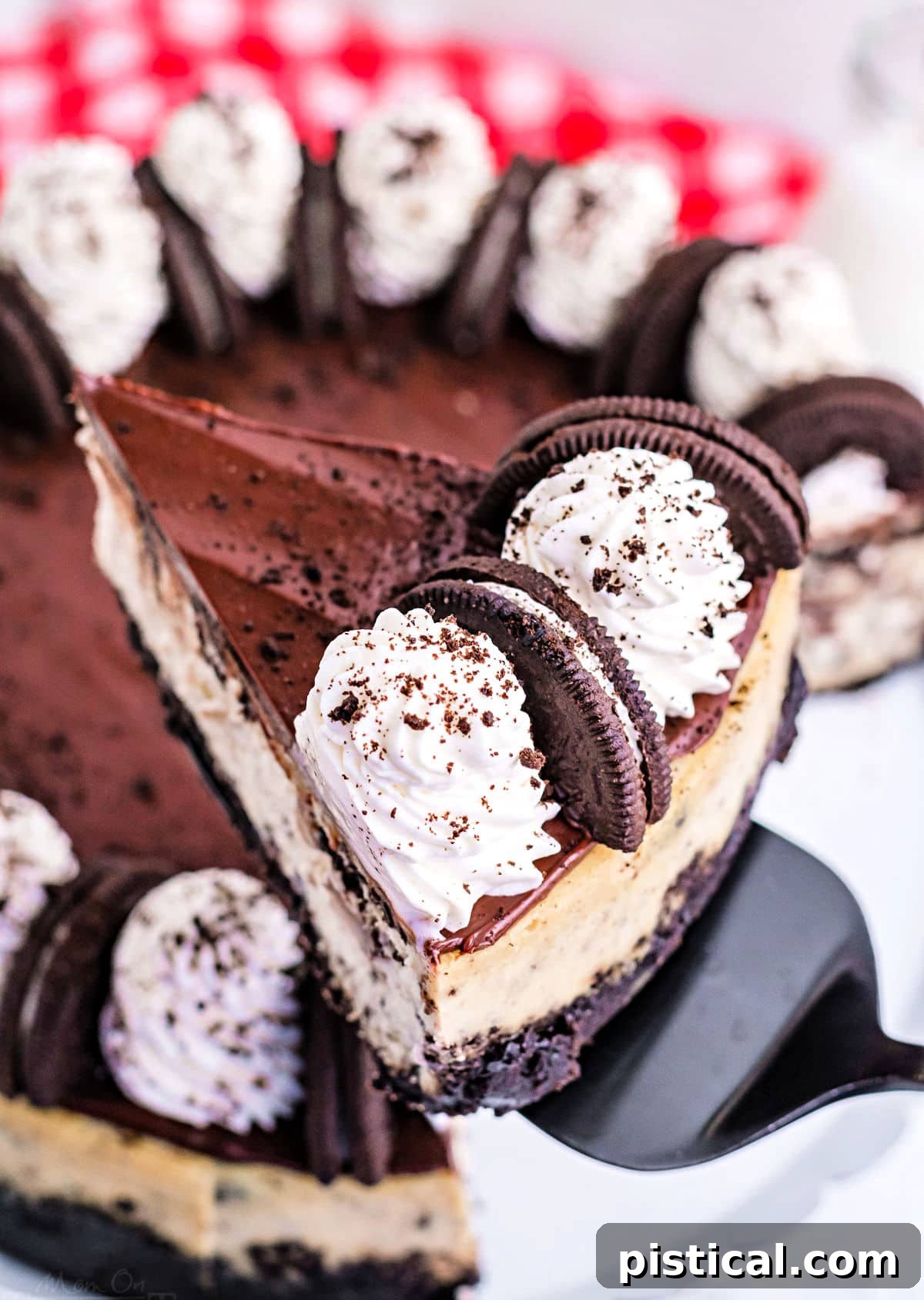 A slice of creamy Oreo cheesecake gracefully lifted above the main cake plate, showcasing its layers and rich topping.