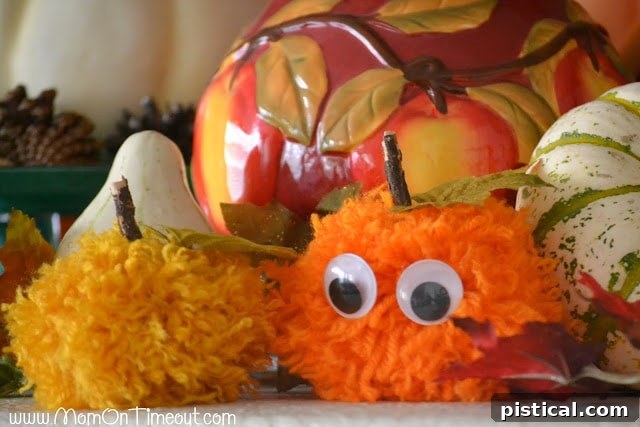 Cute Pom Pom Pumpkins: A Kids Halloween Craft 9 A close-up of a pom pom pumpkin with googly eyes and a leaf, highlighting its cute design.