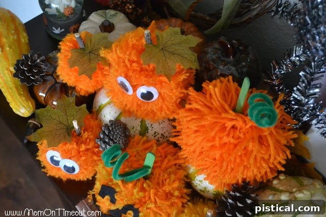 Cute Pom Pom Pumpkins: A Kids Halloween Craft 10 An overhead view of a collection of handmade pom pom pumpkins, highlighting their diverse shapes and embellishments.