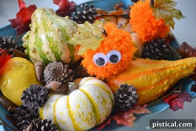 Cute Pom Pom Pumpkins: A Kids Halloween Craft 2 Assortment of handmade pom pom pumpkins with various stems and decorations, perfect for autumn decor.