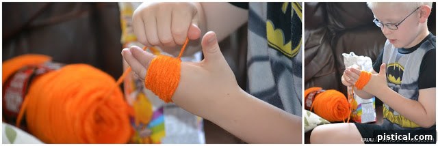 Cute Pom Pom Pumpkins: A Kids Halloween Craft 3 Child's hands wrapping yarn around fingers to create a pom pom, illustrating the first step of the craft.