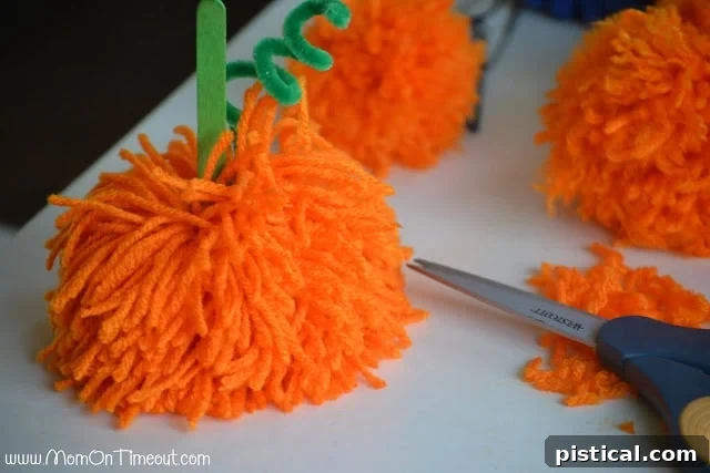 Cute Pom Pom Pumpkins: A Kids Halloween Craft 8 A finished pom pom pumpkin with a stem inserted, ready for final embellishments.