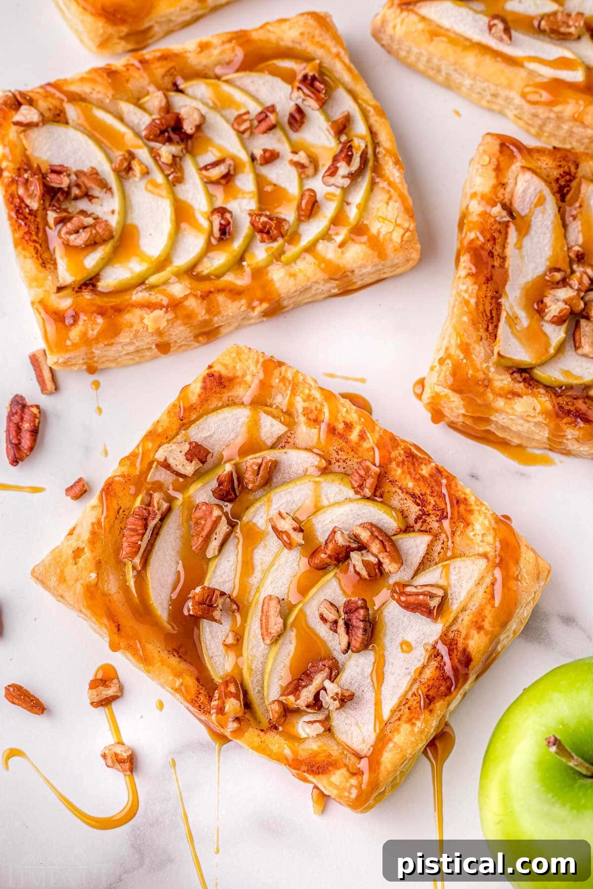Sweet & Simple Caramel Apple Tart 3 puff pastry apple tart recipe sitting on marble surface with drizzle of caramel sauce.