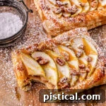 apple tart drizzled with caramel sauce and dusted with powdered sugar on a wood cutting board.