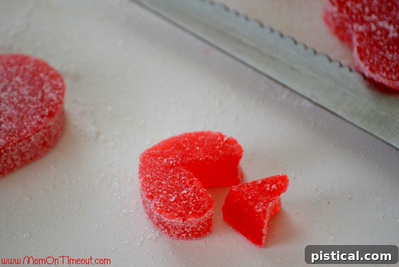 Close-up of heart-shaped gumdrops being prepared with a pretzel stick to form Cupid's Arrows