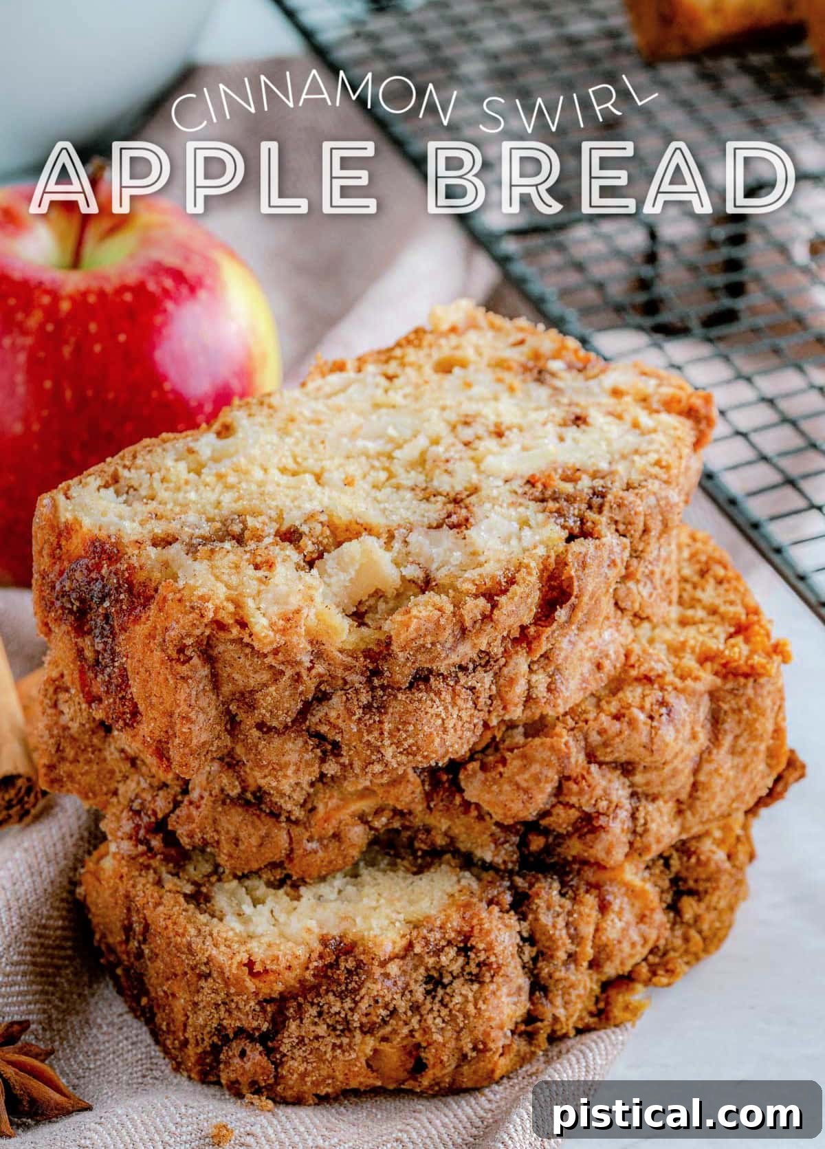 Three slices of homemade apple bread with cinnamon swirl, stacked next to a cooling rack, with a whole red apple in the background. The bread is golden brown and visibly moist.