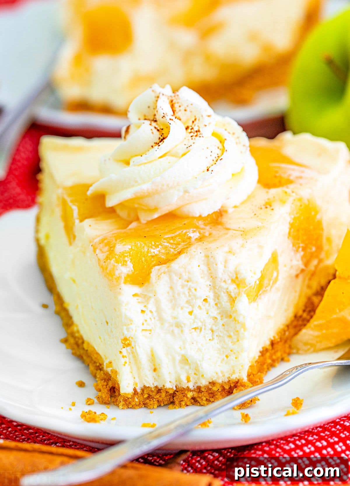 A close-up view highlighting the creamy texture of a slice of no bake apple cheesecake, with a fork removing a small bite, emphasizing its irresistible appeal.