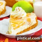 A slice of apple cheesecake sitting on a white plate with fork. cheesecake is garnished with whipped cream and apple pie spice. whole cheesecake in background.