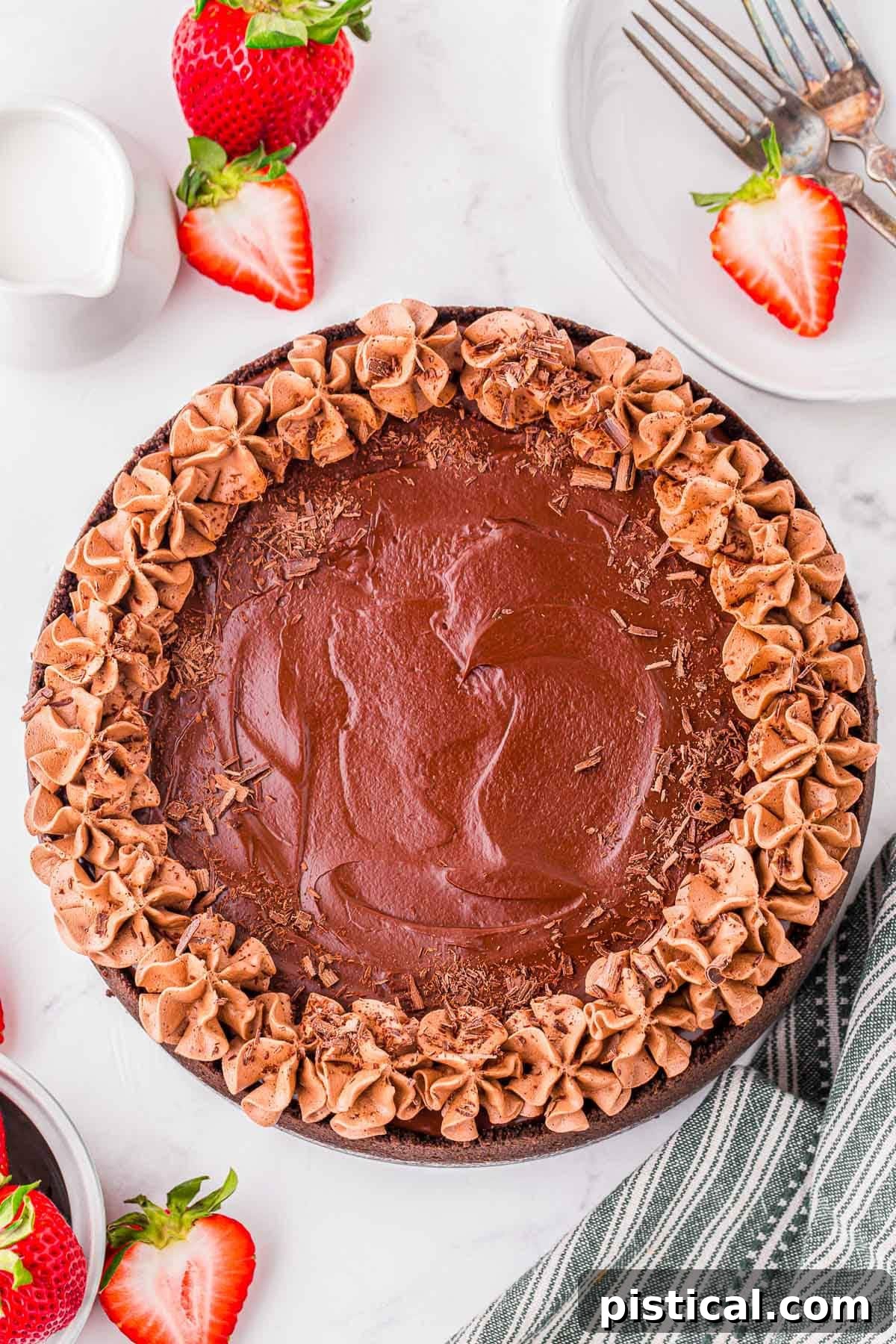 Top down look at whole chocolate cheesecake topped with chocolate shavings and whipped chocolate ganache.
