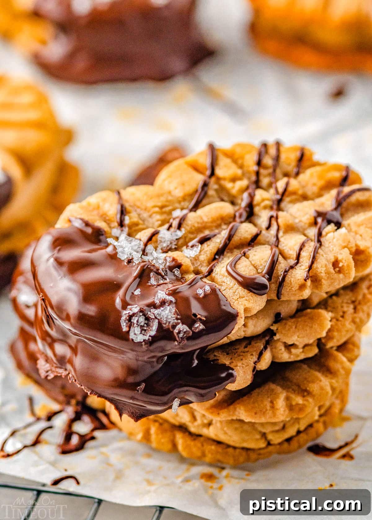 close up look at three nutter butter cookies stacked each dipped in chocolate and sprinkled with flaky sea salt.