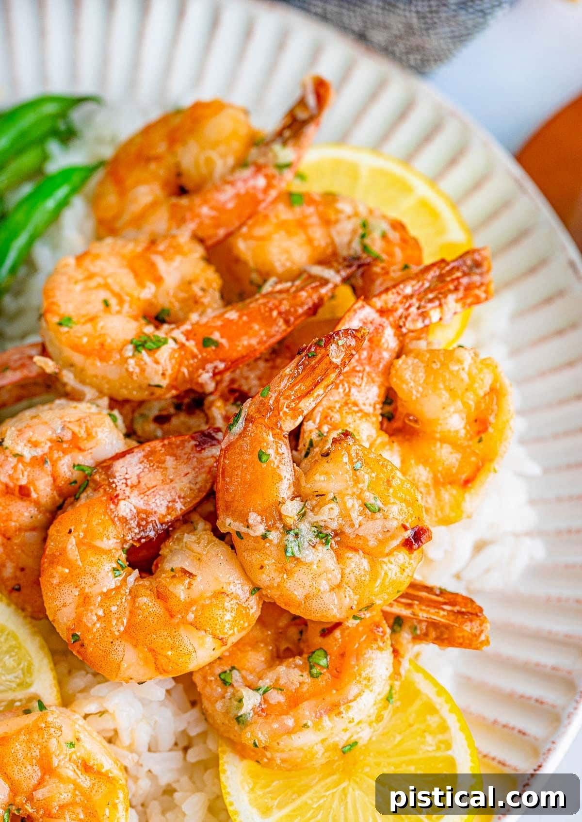 Close-up, top-down view of golden air fryer shrimp with a glistening garlic butter sauce and fresh lemon slices.