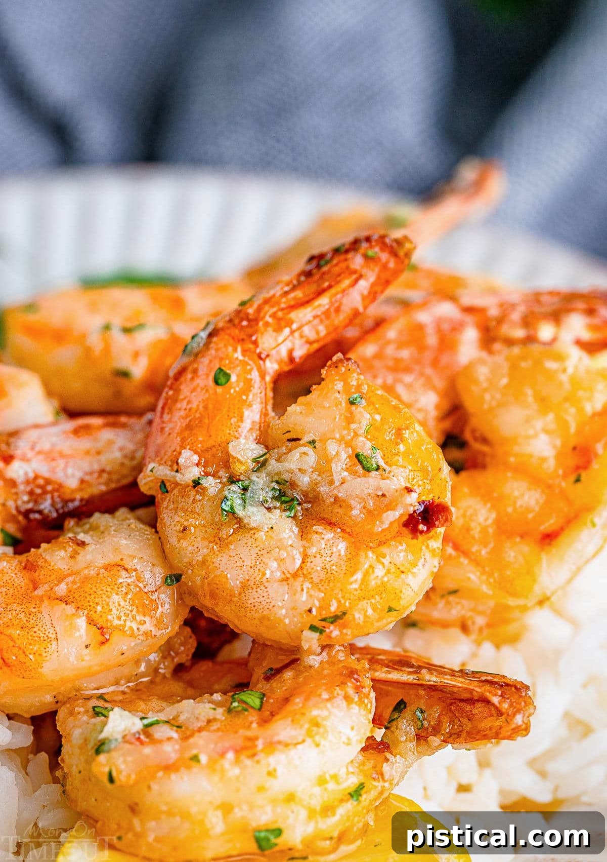 Succulent large air fryer shrimp, smothered in garlic butter sauce, served over a bed of fluffy white rice, ready for a delicious meal.