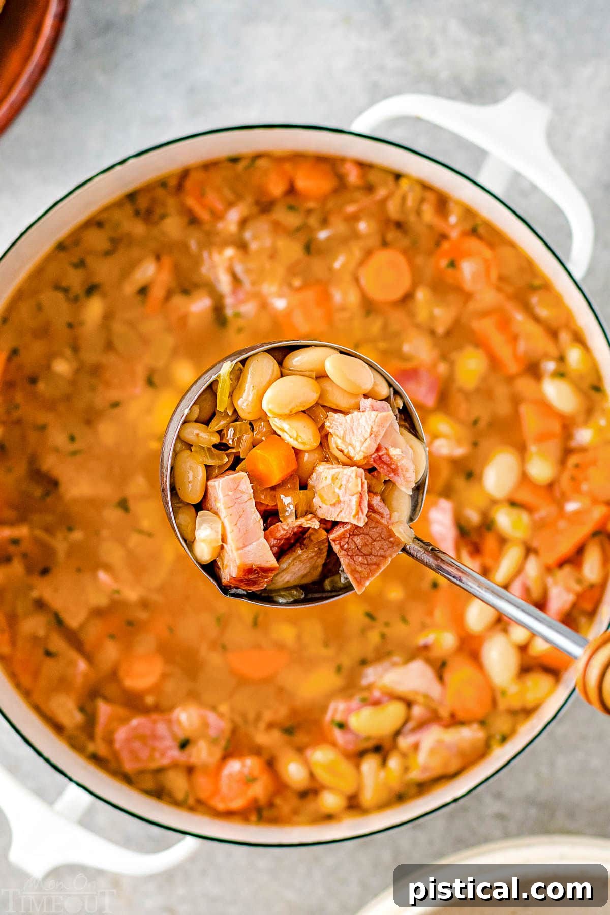 top down look at ladle being held above pot of soup in white dutch oven.